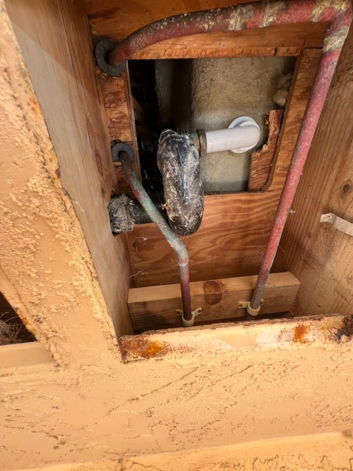 Open wall exposing corroded copper pipes during slab leak repair