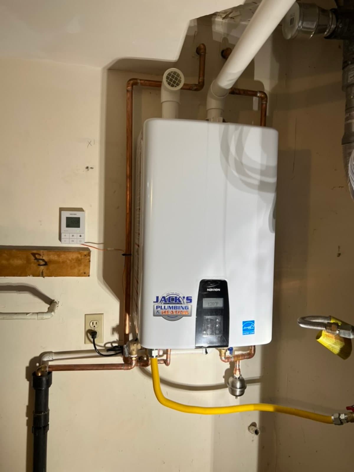 Full tankless water heater installation showing gas line, copper pipes, and NAVIEN controller