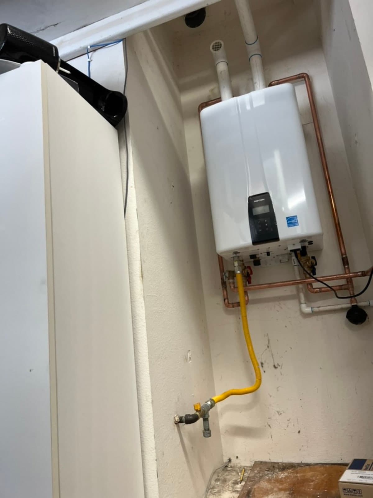 NAVIEN tankless water heater installed in utility closet with PVC venting