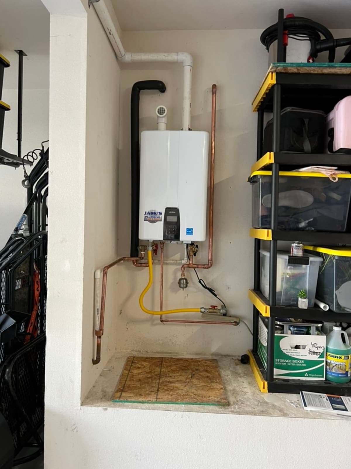 Tankless water heater in garage alcove with yellow gas flex line