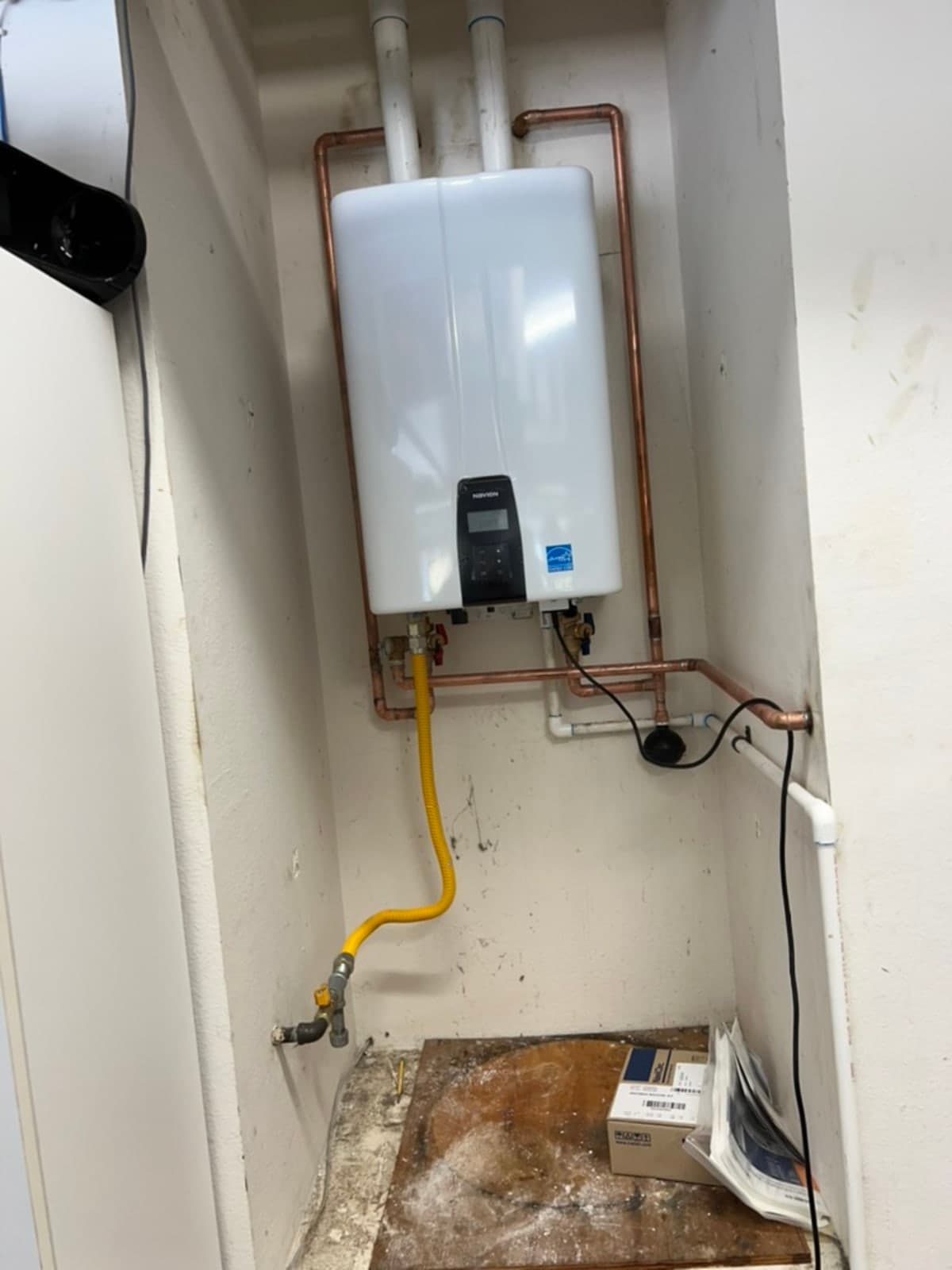Wall-mounted NAVIEN tankless unit with copper piping and PVC condensate drain