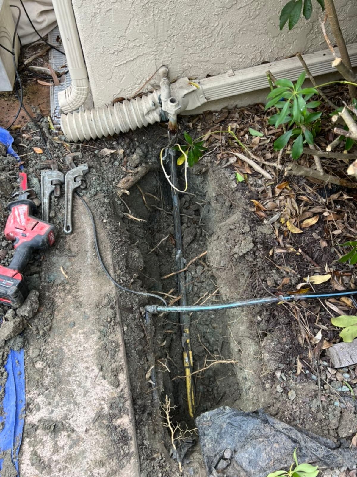 Trench dig exposing water service line at foundation for replacement