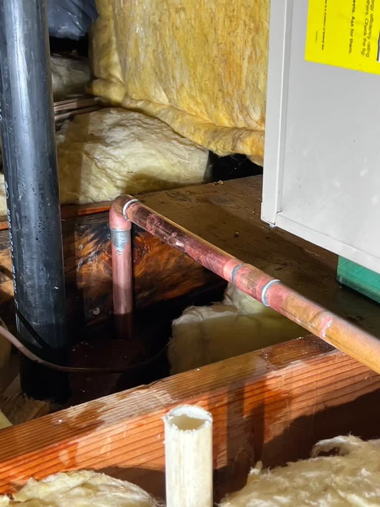 Standing water pooled around copper supply pipes beneath a North County San Diego home, showing an active under-slab leak