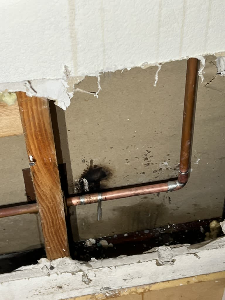 Completed copper pipe repair at slab level behind opened drywall in a Carlsbad home